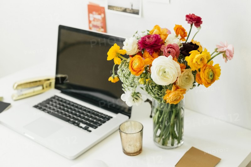 Flowers in jar near laptop in office