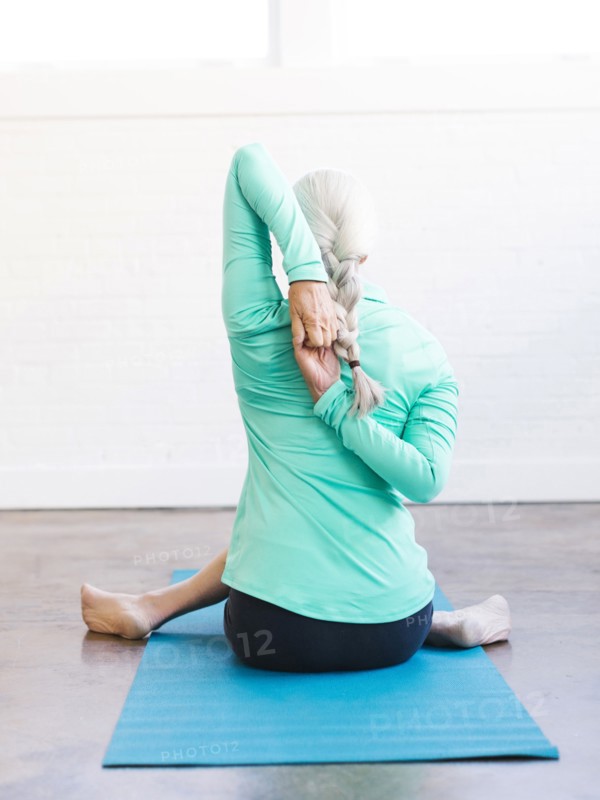 Senior woman practicing yoga on mat