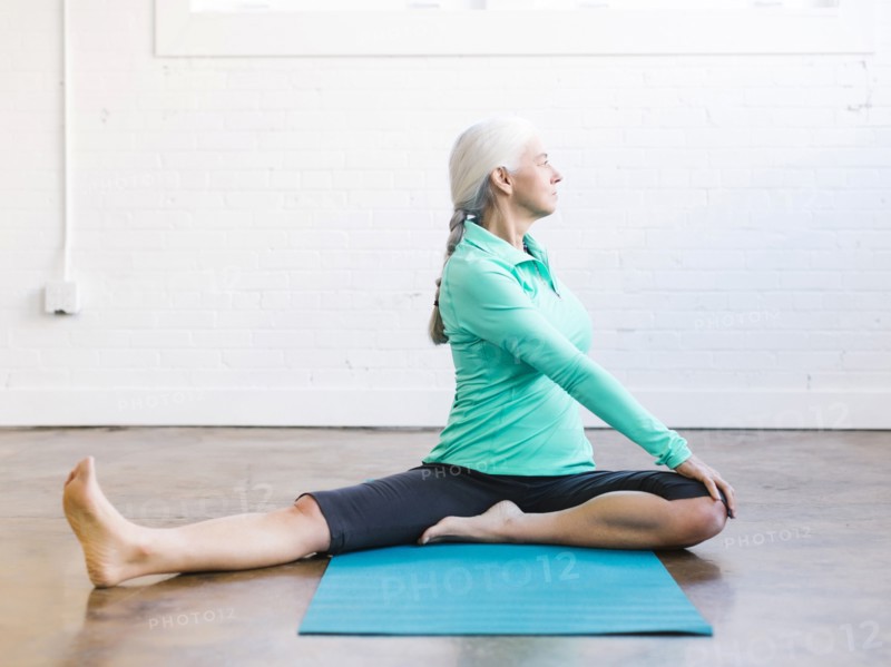 Senior woman practicing yoga on mat