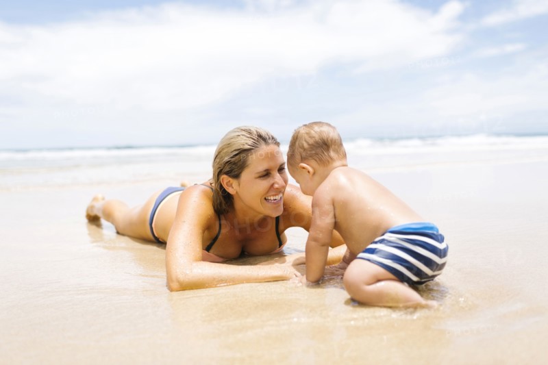 Mother playing with son (12-17 months) on beach