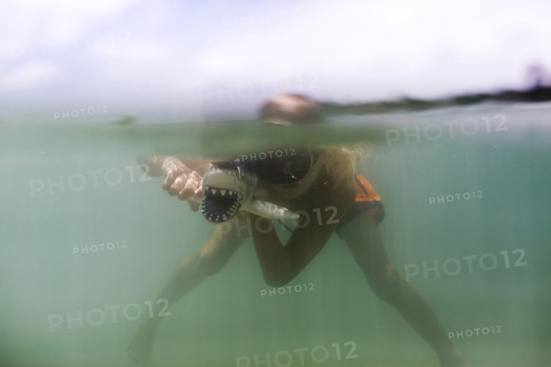 Boy (8-9) playing with toy shark in sea