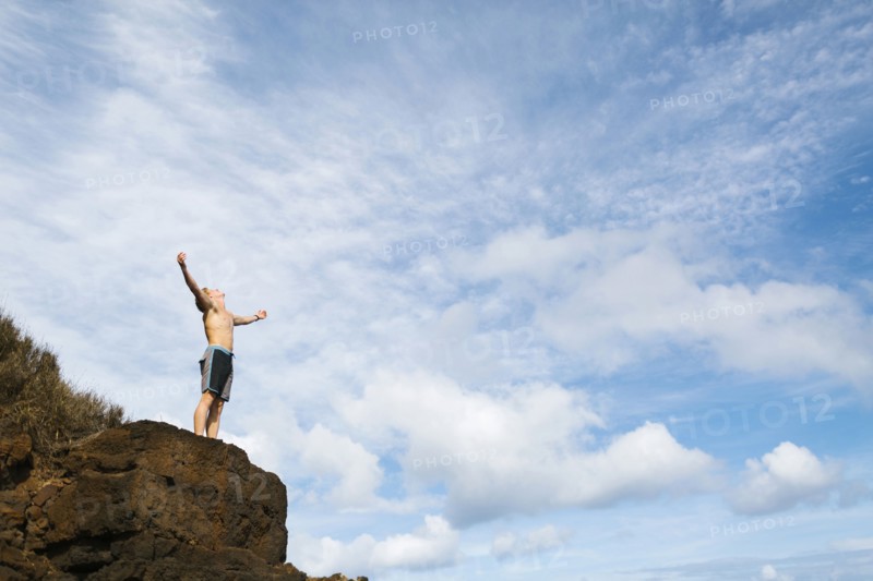 Man standing on rock against blue sky