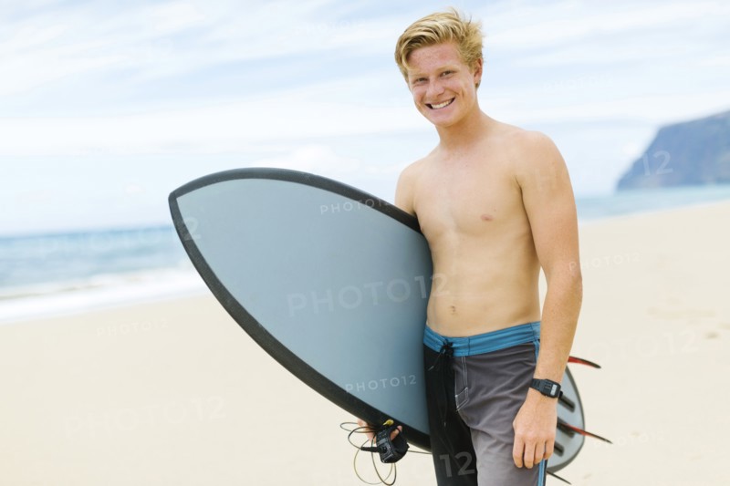 Man standing on beach and holding surfboard