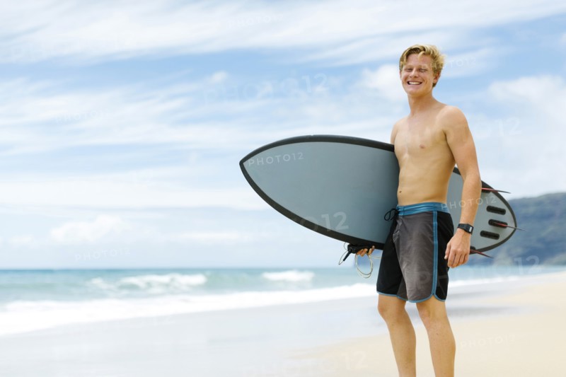 Man standing on beach and holding surfboard