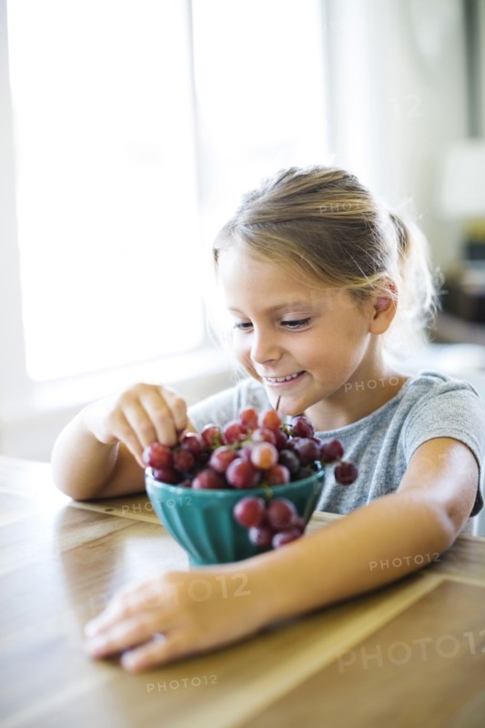 Young girl (6-7) eating fresh grapes