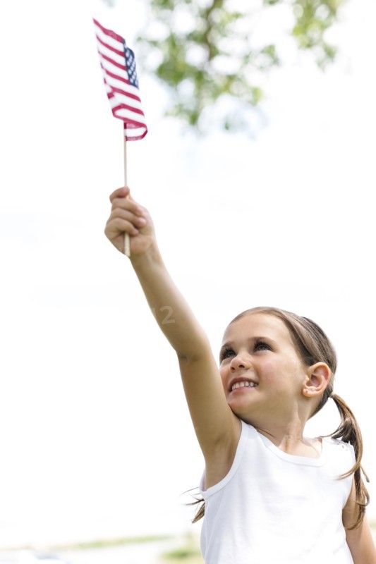 Smiling girl (4-5) holding american flag