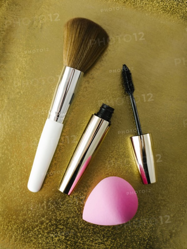 Mascara, make-up brush and small sponge on shiny background
