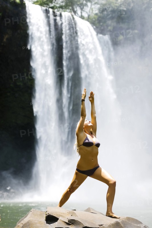 USA, Hawaii, Kauai, Woman practicing yoga next to waterfall