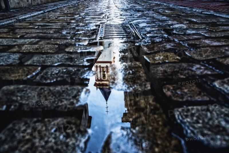 Spain, Andalusia, Seville, La Macarena, Church reflecting on wet cobblestone street