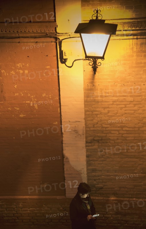Woman standing by brick wall and using smart phone