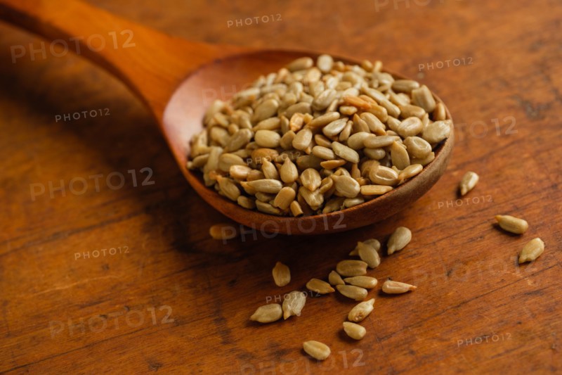Wooden spoon full of sunflower seeds on table