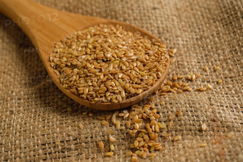 Wooden spoon full of flax seeds on burlap