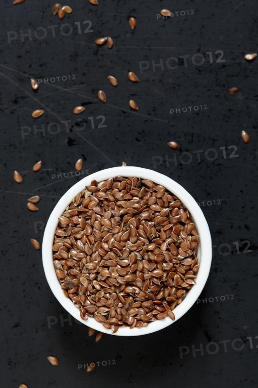 Bowl full of flax seeds on black background