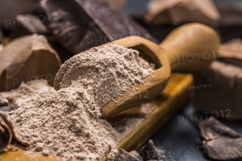 Still life with wooden scoop full with chocolate powder
