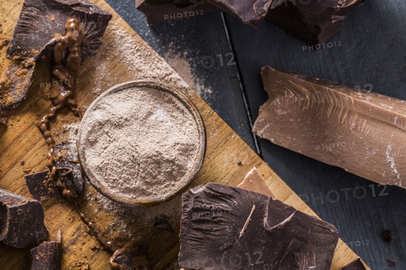 Various chocolate pieces and chocolate powder on cutting board