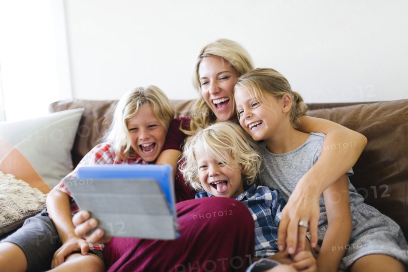 Mother and children (4-5, 6-7, 8-9) taking selfie with digital tablet