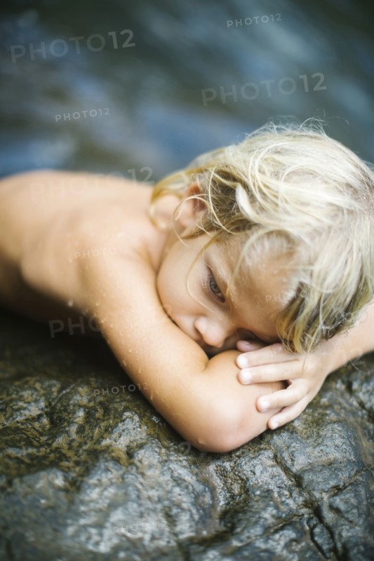 Boy (4-5) resting on rocks