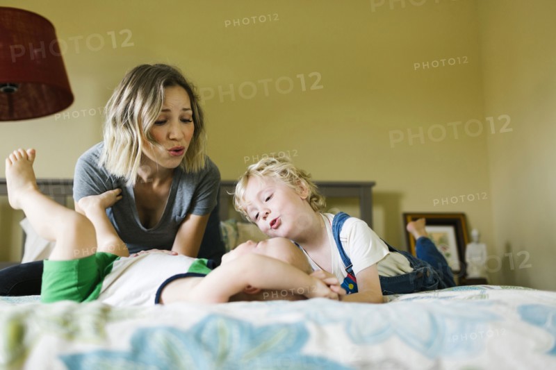Mother playing with sons (12-17 months, 4-5) in bedroom