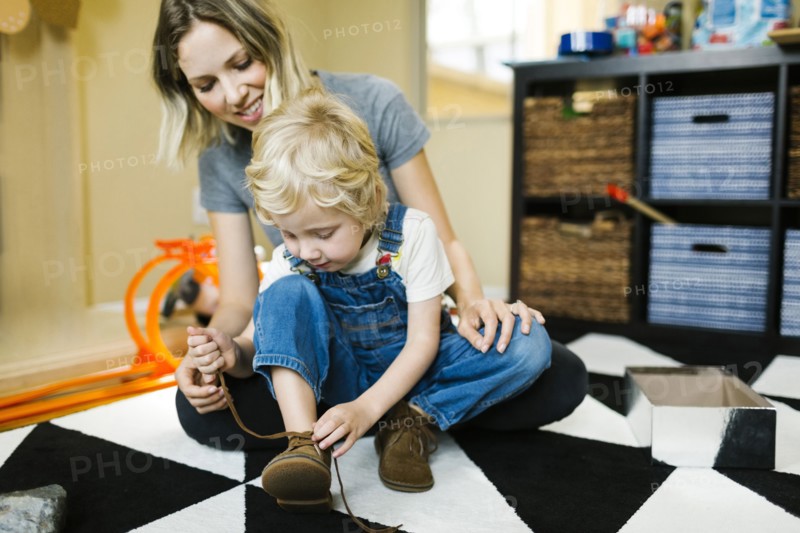 Mother learning son (4-5) to tie shoes