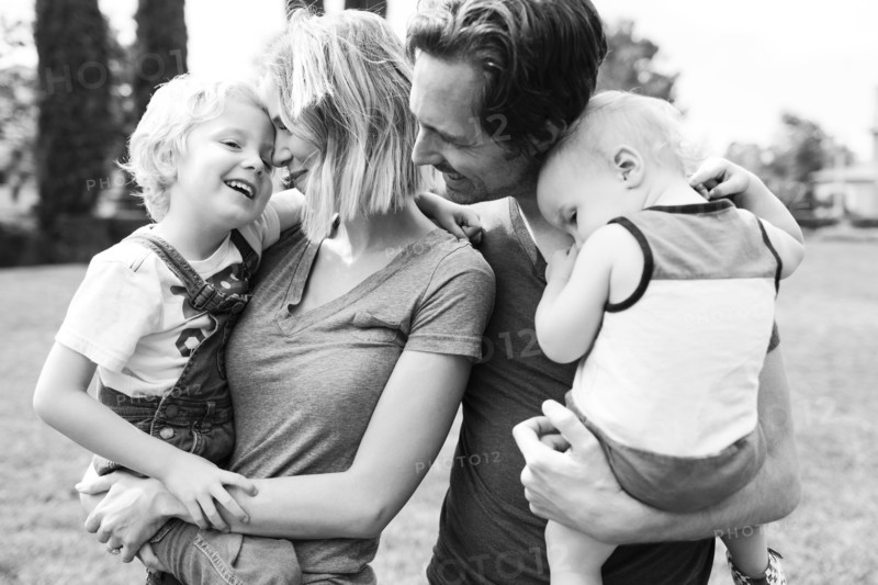 Portrait of parents with sons (12-17 months, 4-5) in park