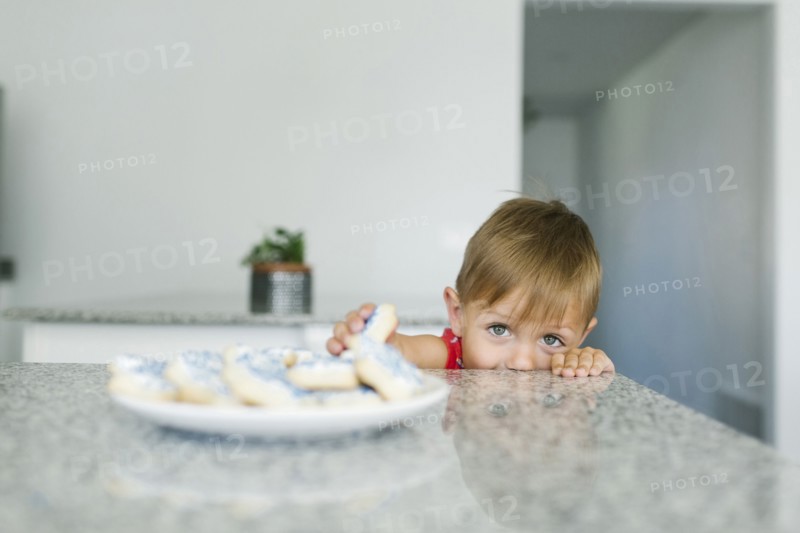 Boy (2-3) reaching for cookies on kitchen counter