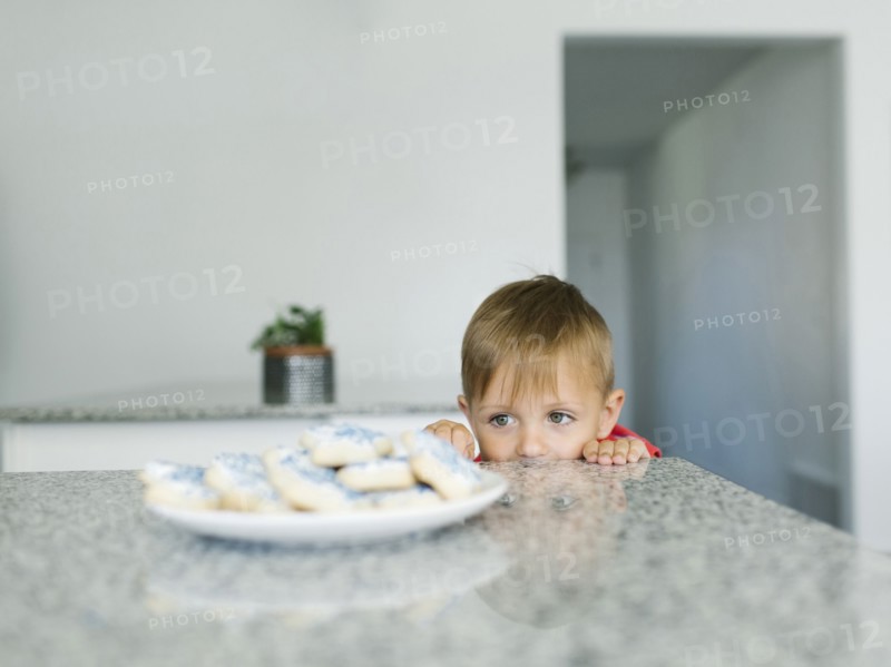 Boy (2-3) looking at cookies on kitchen counter