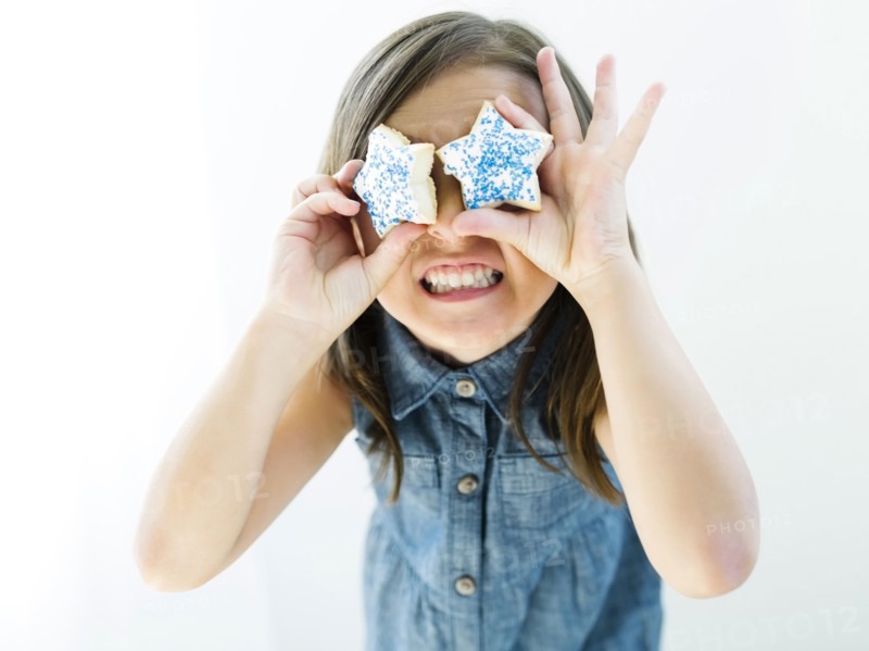 Portrait of girl (6-7) holding cookies in front of eyes