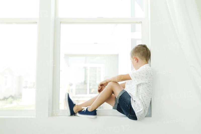 Boy (7-8) looking through window