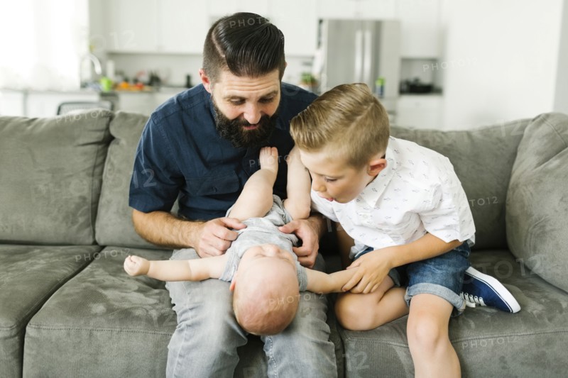 Father and boy (6-7) playing with baby boy (6-11 months) in living room