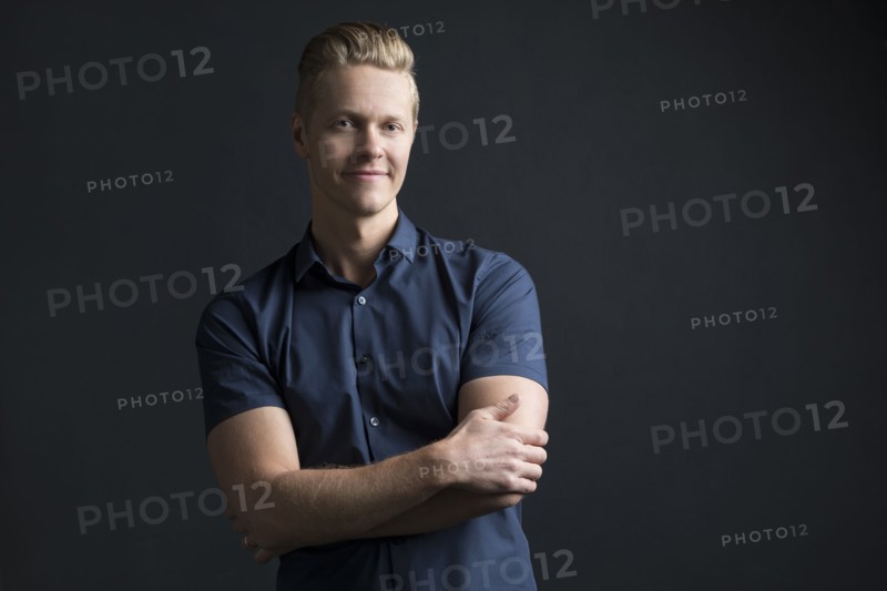 Portrait of man with crossed arms on black background