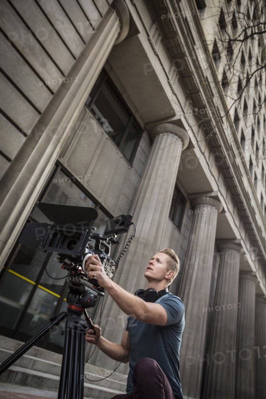 Camera operator filming in front of building