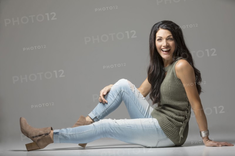 Studio shot of woman sitting on floor and laughing