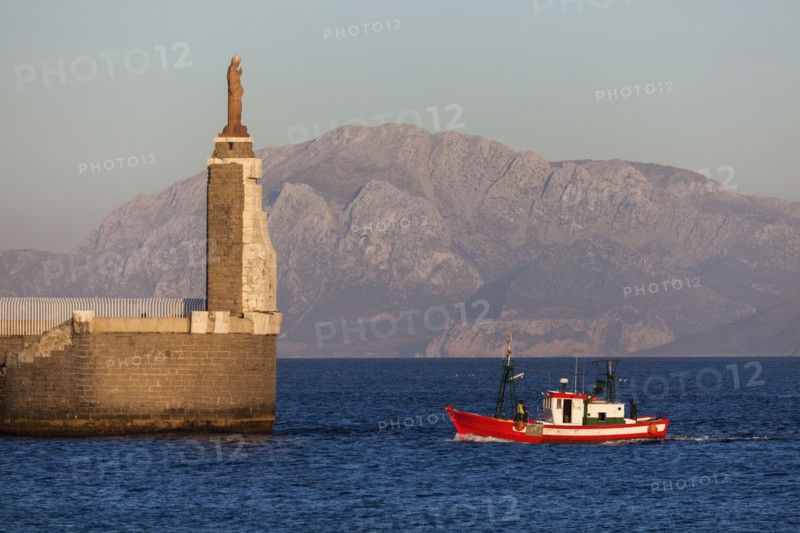 Spain, Andalusia, Tarifa, port of Tarifa, Jesus Christ statue by sea and red fishing boat