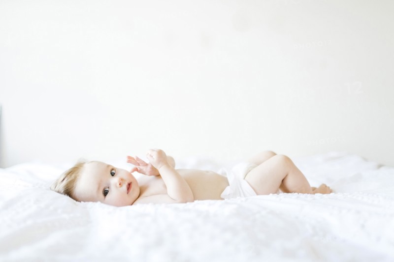 Portrait of baby girl (6-11 Months) lying down on bed