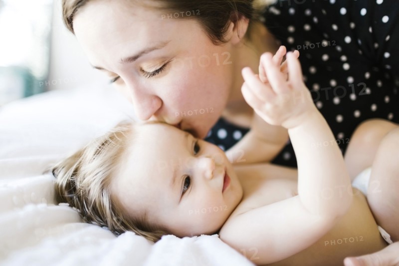 Baby girl (6-11 Months) being kissed by mother