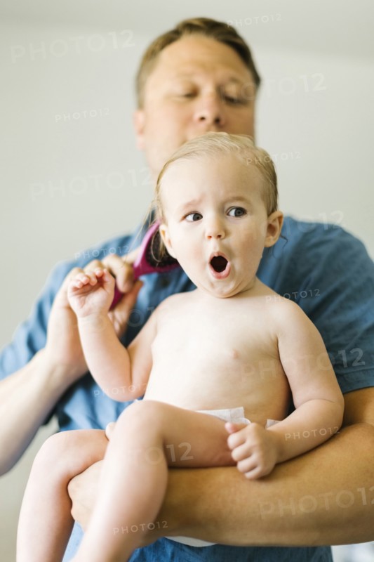 Father and baby girl (12-17 months) brushing hair after bath