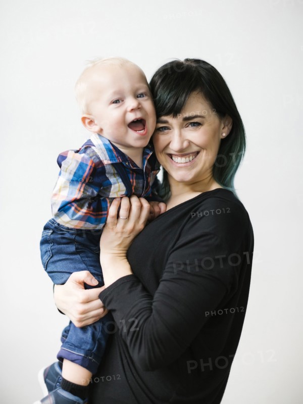 Portrait of mother holding son (12-17 months) against white background