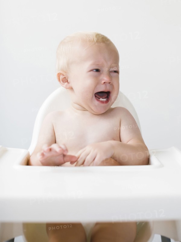 Baby boy (12-17 months) sitting in high chair and crying