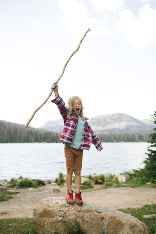 USA, Utah, Midway, Boy with stick (6-7) standing on rock by lake