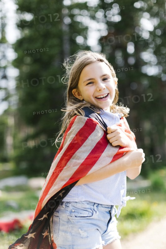 Portrait of girl (8-9) wrapped in us flag in forest