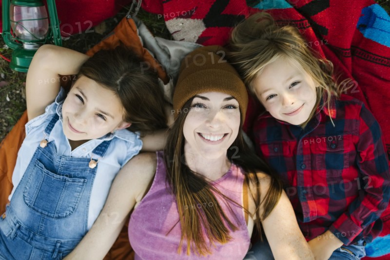 Portrait of woman with son (6-7) and daughter (8-9) lying on blanket