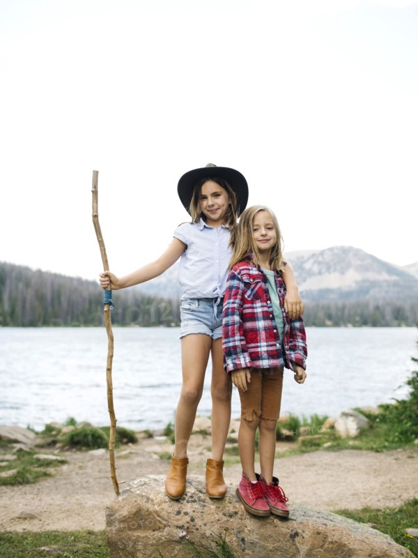 Girl (8-9) and boy (6-7) standing at lakeshore