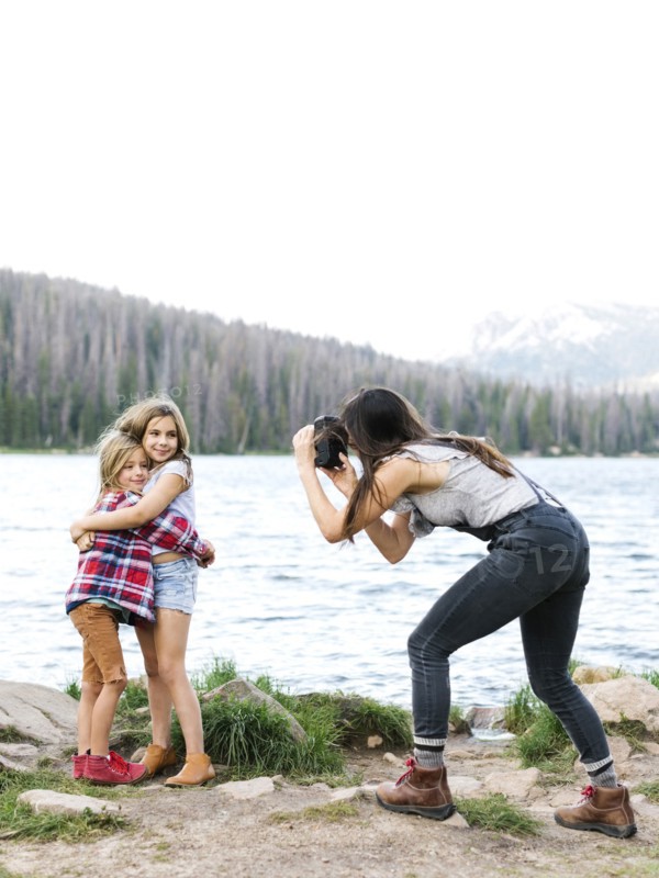 Mother photographing girl (8-9) and boy (6-7) by lake