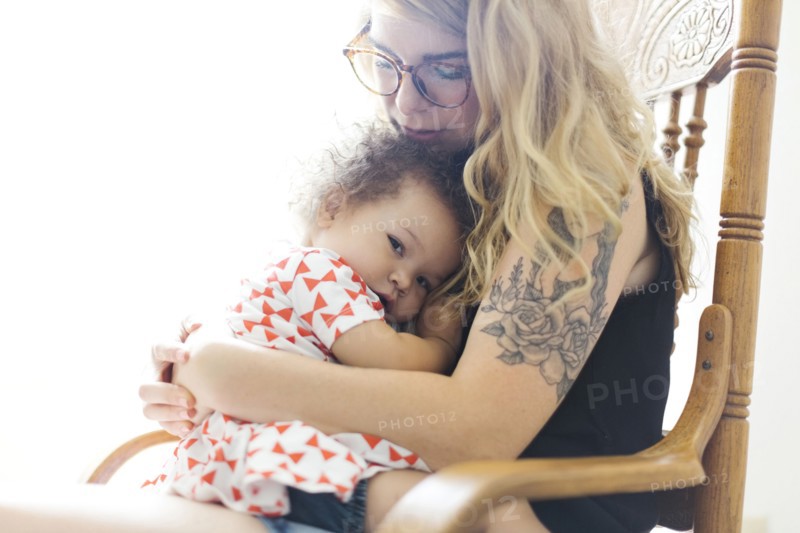 Mother sitting on chair and rocking daughter (12-17 months)