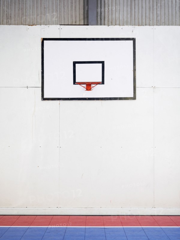 Empty basketball court with basketball hoop hanging on wall