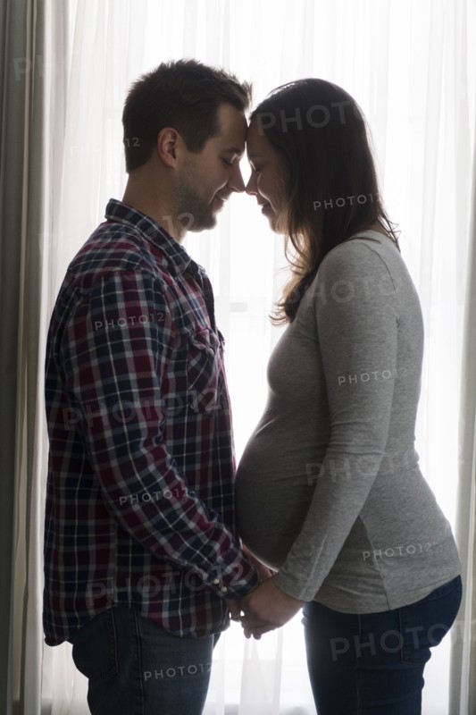 Mid adult couple in front of window, face to face