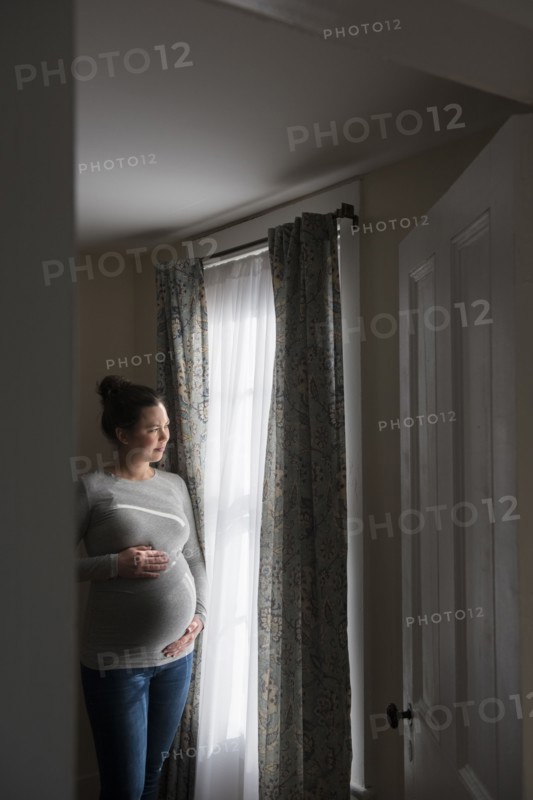 Pregnant woman looking through window