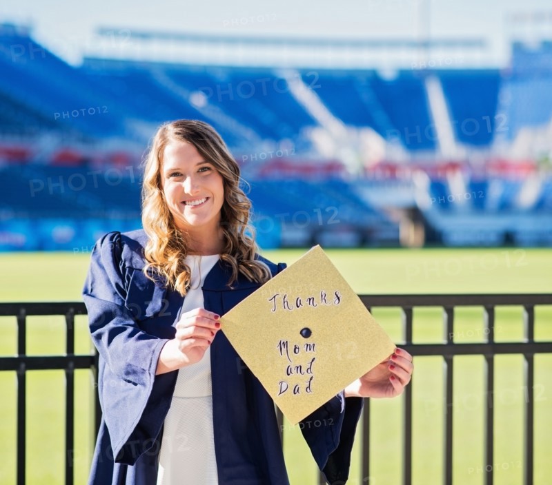 Portrait of graduate student showing message on mortarboard