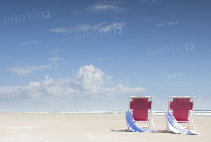 Deck chairs with towels on sandy beach by Atlantic Ocean