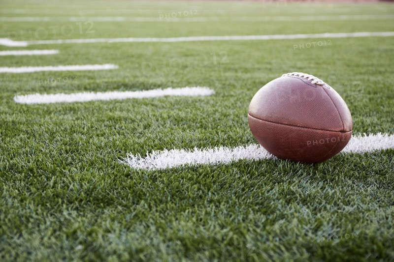 Close up of American football ball on green playing field